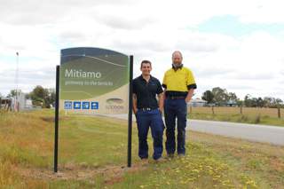 Men standing by the Mitiamo sign