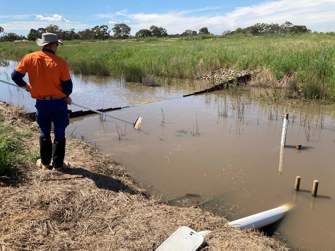 man next to river taking a water sample 