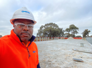 Photograph of Raymond Oguntade at a project site wearing high vis clothing and a hard hat.