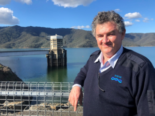 Photograph of Steve Hall standing on dam wall in front of Lake Eildon 