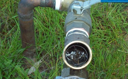 An image of a strainer blocked with grass and debris